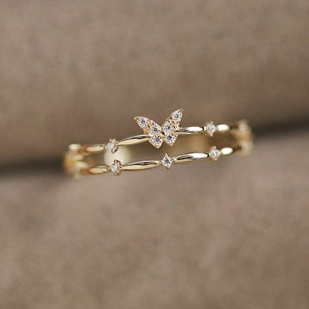 詳細なキュービックジルコニアのアクセントを展示したバタフライリングの金メッキバージョンのクローズアップ。