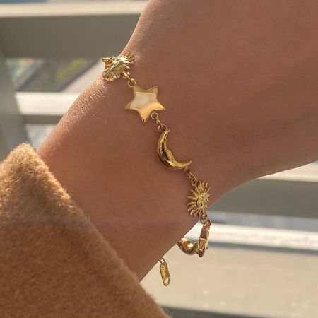 サイズと複雑な月、太陽、星のチャームを展示した金の天体チャームブレスレットの詳細ビュー。