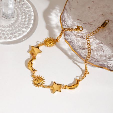 Wholesale gold stainless steel bracelet with delicate celestial charms including a sun, moon, and stars.