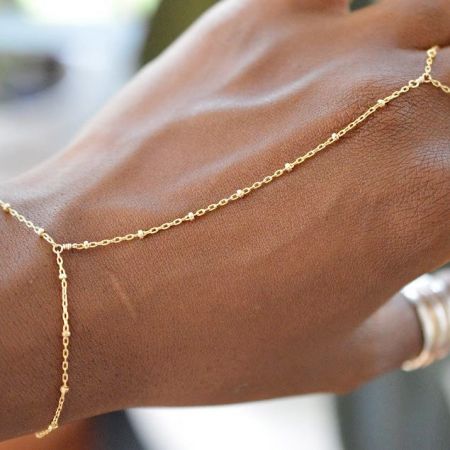 En närbild av det rostfria stål slavar fingerringarmbandet på en hand, som visar dess delikata design.