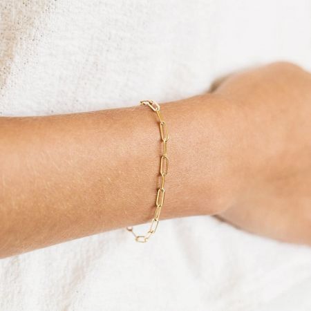 Een vrouw die de gouden paperclip kettingarmband draagt.