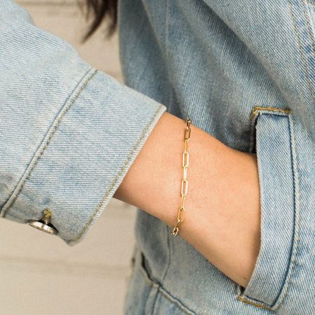 Close-up van de gouden paperclip armband op een pols.