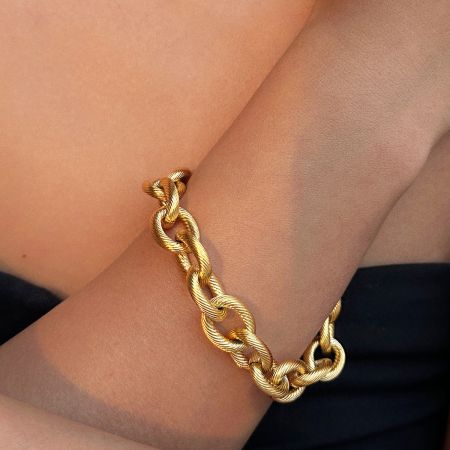 Een model dat de gouden schakels armband uit de set draagt om de schaal en stijl op de pols te tonen.