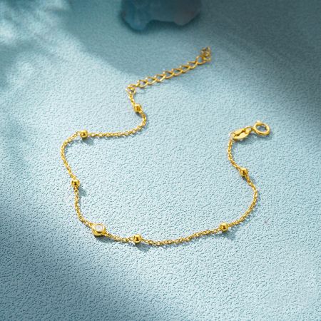 The gold version of the bead chain bracelet, featuring a clear zircon stone.