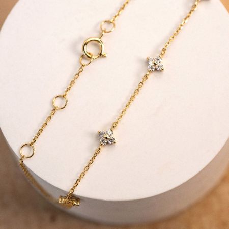 Visão detalhada da corrente de ouro e pedras de zircônia na pulseira de flores.