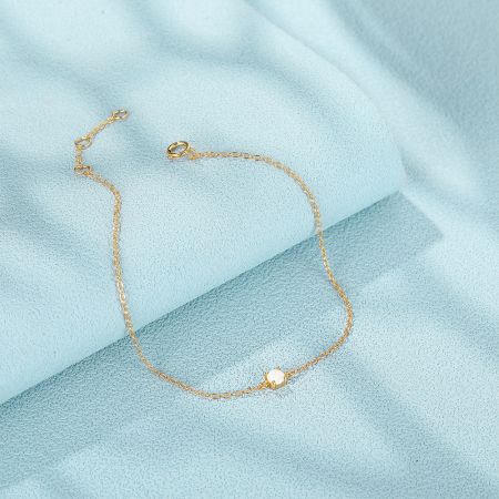 Scatto del prodotto del bracciale a catena dorato con un singolo gemma in opale bianco.