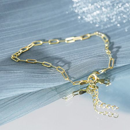 Gedetailleerd uitzicht op de gouden paperclip ketting schakels en sluiting.