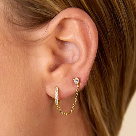 Créoles huggie en argent sterling 925 avec chaîne et clou en CZ (ensemble de 5 pièces) - Un ensemble de cinq boucles d'oreilles huggie en argent sterling 925 avec des clous en CZ blancs étincelants, présenté en finition or sur fond blanc.