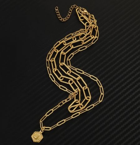 Close-up van de gouden ketting en hexagonale hanger, die de gepolijste afwerking en ingewikkelde details toont.