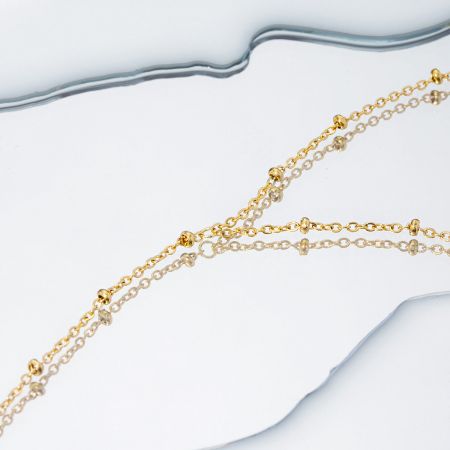 Två guldpläterade pärlchain armband från setet visade tillsammans för att framhäva produktutbudet.