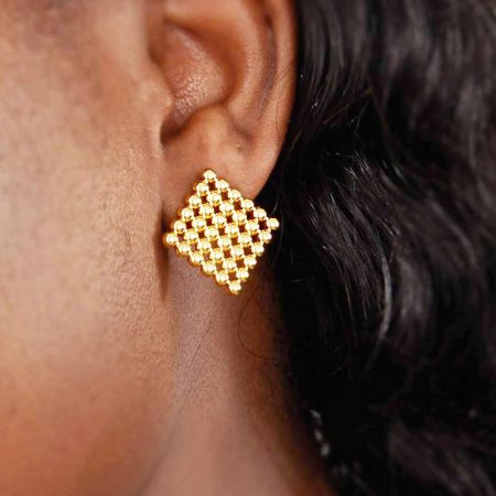 Un modello che indossa gli orecchini a perno quadrati placcati in oro, mostrando la loro dimensione e aspetto.