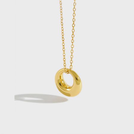 Vue en gros plan du collier pendentif rond plaqué or 18K, soulignant sa couleur éclatante et sa texture lisse.