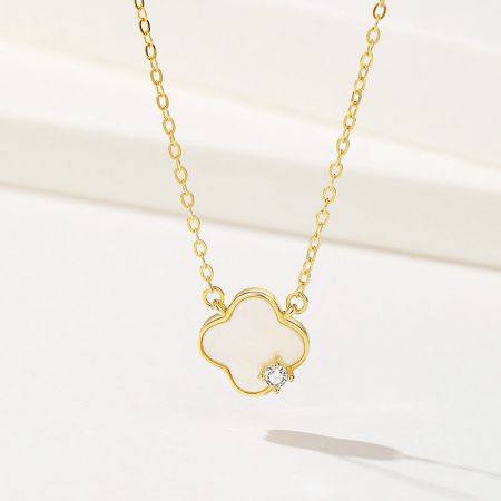 Collar de trébol de cuatro hojas de madreperla de plata esterlina 925. - Un primer plano de un collar de trébol de cuatro hojas de plata esterlina 925 con acabado dorado. El colgante está incrustado con madreperla y presenta una pequeña gema central.