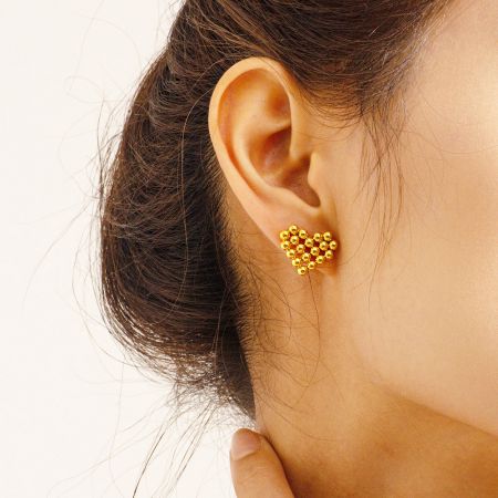 Pendientes de corazón en forma de amor de cuentas redondas de oro de acero inoxidable a prueba de agua (5 pares) - Una mujer que lleva los pendientes de corazón en forma de amor de oro, a prueba de agua, de acero inoxidable, mostrando su aspecto elegante.