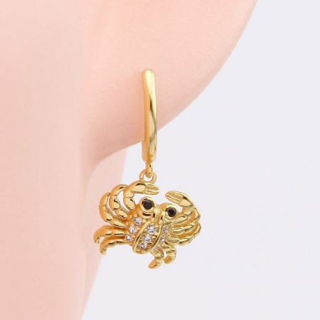 Primo piano dell'orecchino huggie con granchio in oro 925 argento sterling, evidenziando l'intricato incastonamento di gemme.