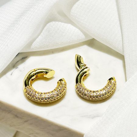 Scatto di dettaglio di un orecchino a cuffia in argento sterling placcato oro a forma di mezzaluna con zirconia cubica scintillante.