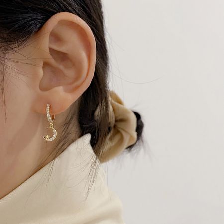 Modelo usando el pendiente huggie de luna creciente de oro para mostrar la escala y el estilo.