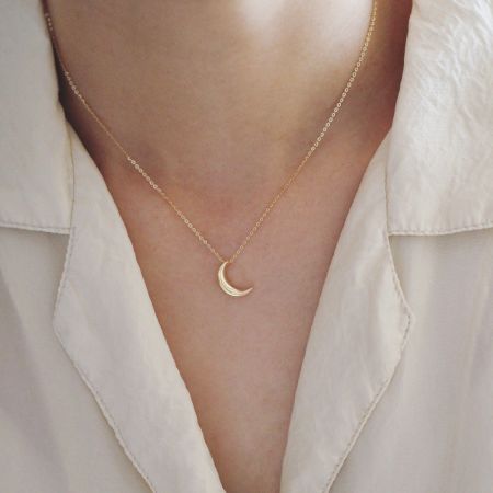 Modello che indossa la collana con pendente a forma di luna crescente dorata, mostrando la sua lunghezza e stile.