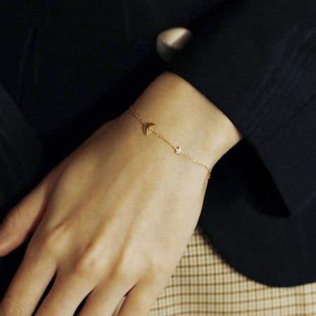 Vista detalhada da pulseira de charme com lua e estrela em um pulso.