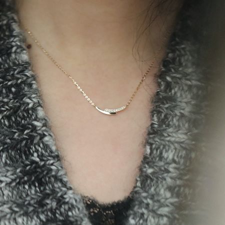 A model wearing the gold necklace with a diamond-studded crescent pendant.