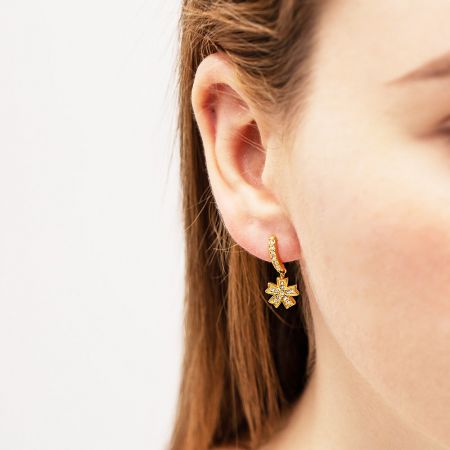 Pendientes de gota de flor de circonio dorado impermeables de acero inoxidable - Un primer plano detallado de un pendiente de gota de flor de acero inoxidable chapado en oro con una piedra central de circonio.