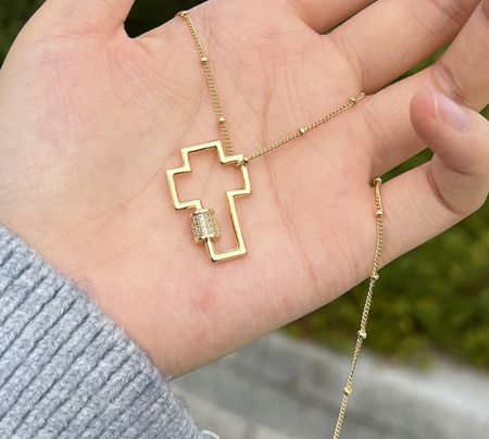 Vista dettagliata di un pendente a croce d'oro con un connettore incastonato di diamanti, un esempio di gioielleria religiosa personalizzata.