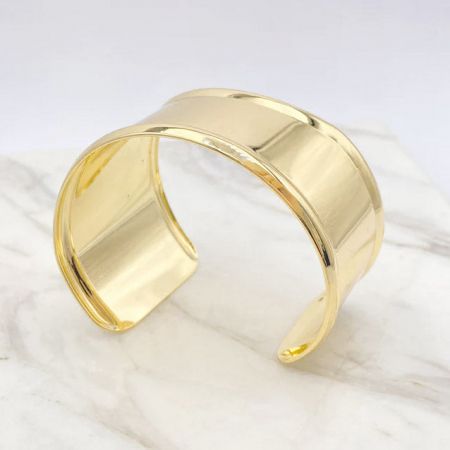 Vista angolata del bracciale a manica in oro lucido, che evidenzia il suo design moderno.
