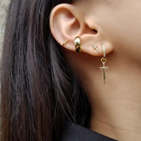 Una collezione di vari orecchini a tema pugnale d'oro esposti insieme.