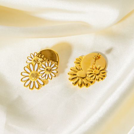 Detailopname van de gouden madeliefjes oorbellen met witte emaille bloemblaadjes.