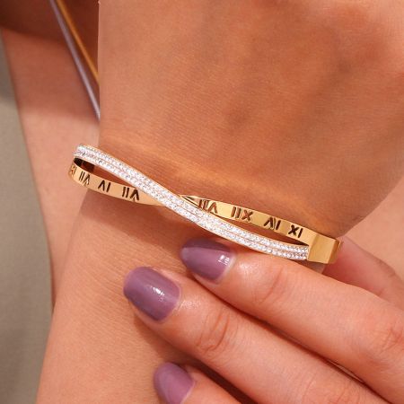 金とダイヤモンドのバングルブレスレットの角度をつけたビューで、交差したCZの詳細によって作られた無限大のシンボルに焦点を当てています。