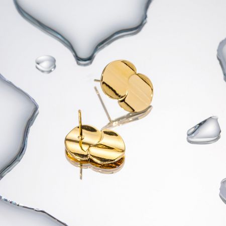 Pendientes pequeños de disco doble de oro en acero inoxidable. - Un par de elegantes pendientes de acero inoxidable con un diseño de doble círculo chapado en oro pulido, presentados sobre un fondo limpio y claro.