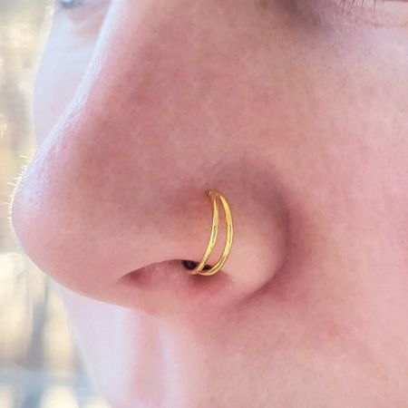 Modello che indossa l'anello nasale a doppio anello d'oro, evidenziando la sua vestibilità comoda e sicura.
