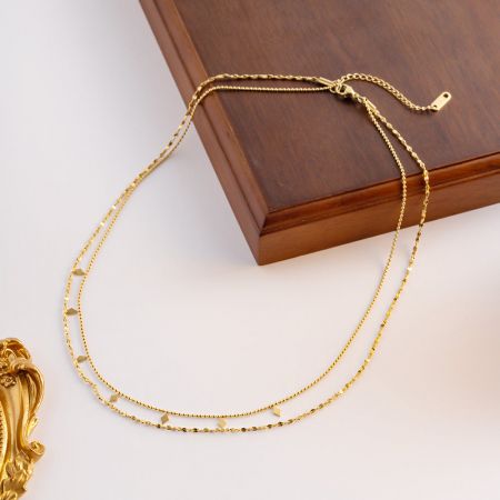 Eine goldene Doppelstrang-Halskette mit komplizierten, diamantförmigen Perlen.