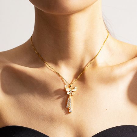 Gros plan d'un collier pendentif en or en forme de libellule avec des accents en cristal, faisant partie de la collection de colliers en acier inoxydable.