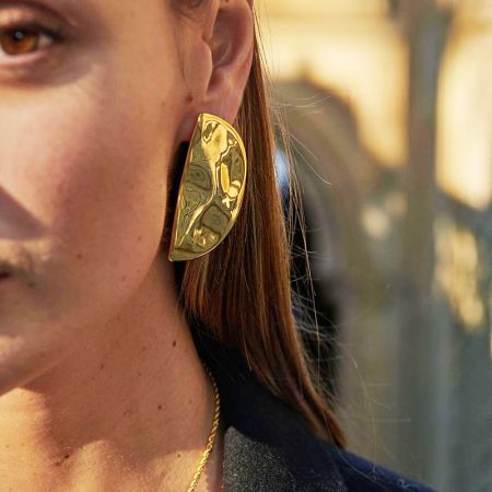 Pendientes de media luna con acabado martillado brillante de acero inoxidable (5 pares) - Una vista en primer plano de una mujer usando un pendiente de media luna de acero inoxidable dorado con un acabado martillado brillante, mostrando su textura y diseño.