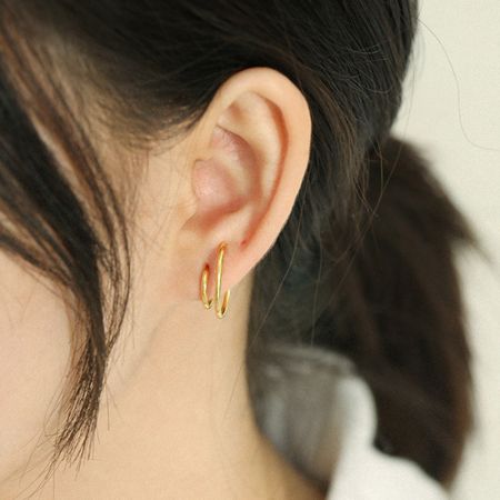 Close-up de uma mulher usando o brinco de argola dupla C minimalista em ouro, destacando seu visual elegante para o uso diário.