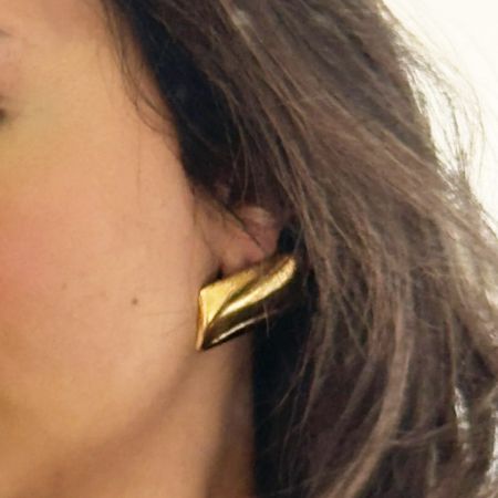 A model wearing the chunky rectangular stud earring in a radiant gold finish.