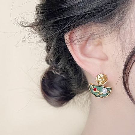 パールとジルコンをあしらった詳細なハーフムーンデザインの金メッキエナメルイヤリングのクローズアップ。