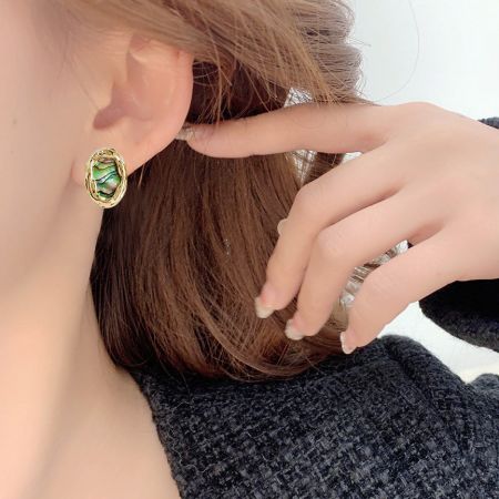 Model wearing a 14k gold-plated oval stud earring with a vibrant green abalone shell inlay.