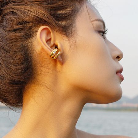 Modelo mostrando el elegante arete de perla de acero inoxidable dorado.