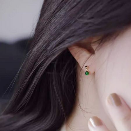Estilos Clásicos Minimalistas al por Mayor Pendientes de Jade Pequeños de Plata Esterlina 925 - Un primer plano de una mujer usando un pequeño pendiente de jade de plata esterlina 925 clásico y minimalista, mostrando su diseño elegante y la vibrante piedra verde.