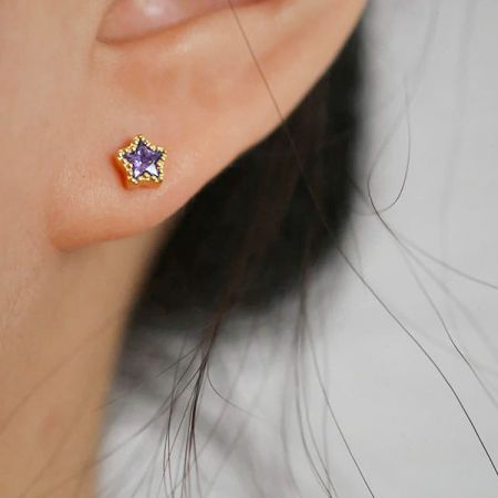 Modello che mostra l'elegante orecchino a stella con pietra preziosa viola.