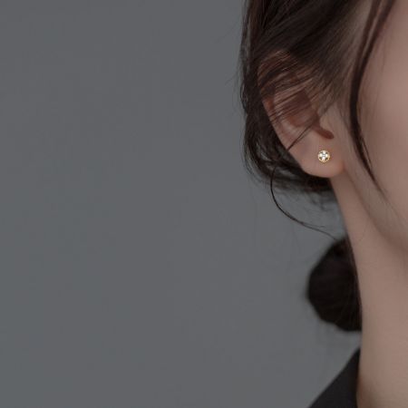 Macro shot of the gold four-leaf clover earring highlighting the central gemstone.