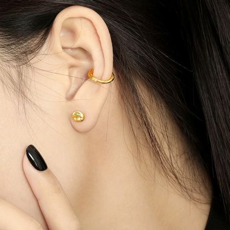 Een vrouw met de gestructureerde gouden ronde stud oorbellen, die hun geschiktheid voor dagelijks gebruik demonstreert.