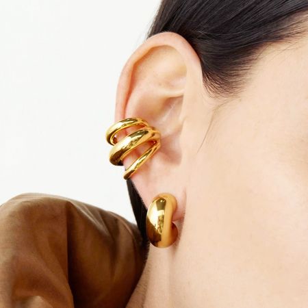 Gedetailleerde close-up van de gouden geometrische drie-laags oorcuff.
