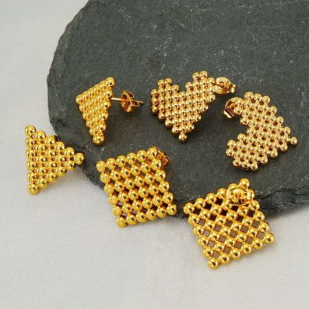 A collection of various gold beaded earrings, including the triangular stud design.