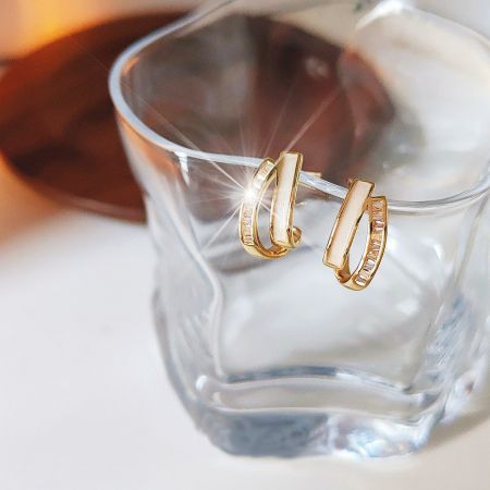 Lifestyle photo of the white enamel gold cross earrings elegantly displayed.