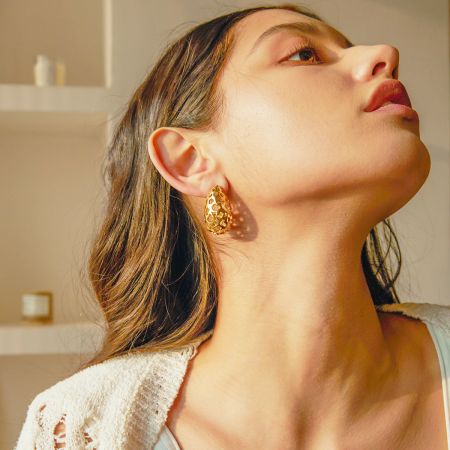 Pendientes de botón de agua en forma de lágrima dorada de acero inoxidable (5 pares) - Modelo mostrando los elegantes pendientes de botón de agua en forma de lágrima dorada de acero inoxidable.