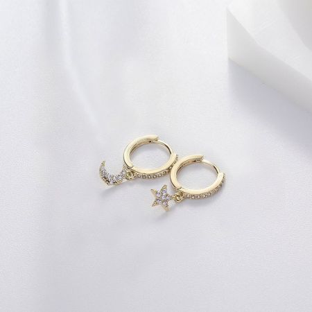 Une présentation élégante des boucles d'oreilles Huggie Lune et Étoile en or sur un fond neutre.