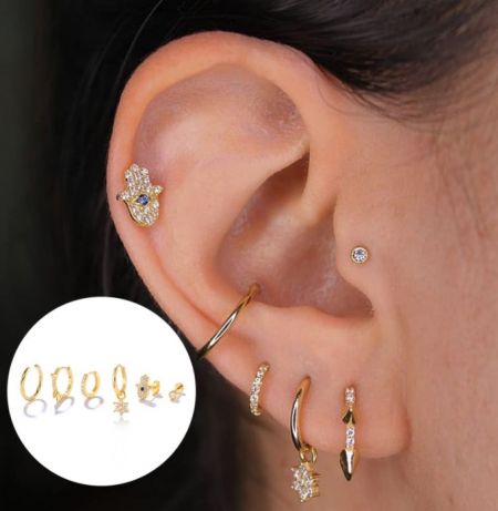 Modelo que muestra múltiples aretes huggie de oro del conjunto en una oreja para un look en capas.